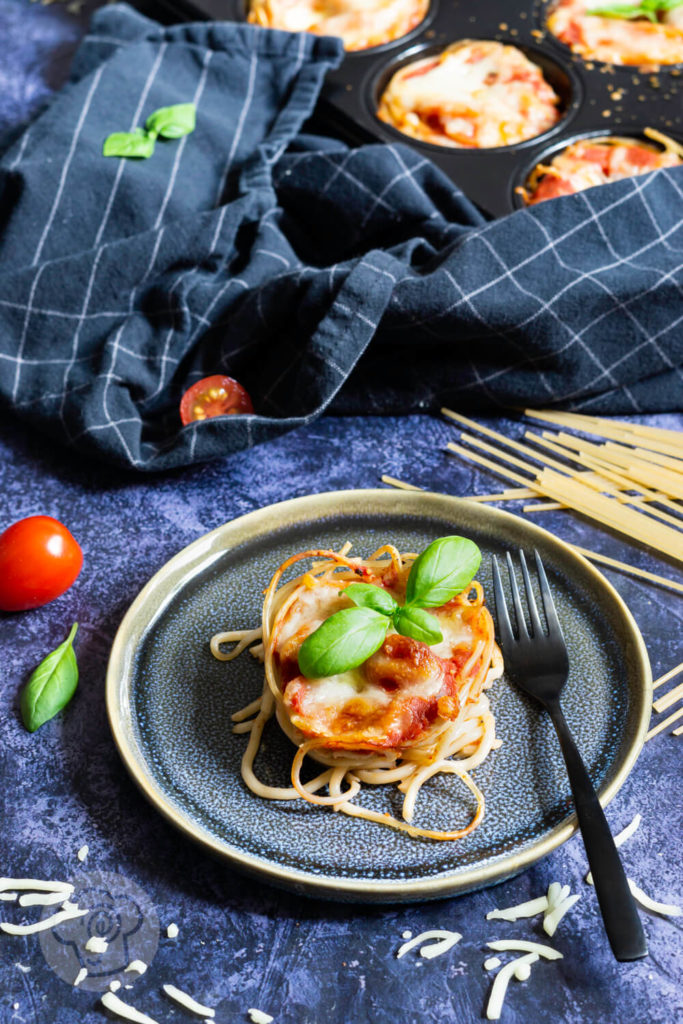 Spaghetti Muffin, einzeln auf einem Teller mit einer Gabel und Basilikum