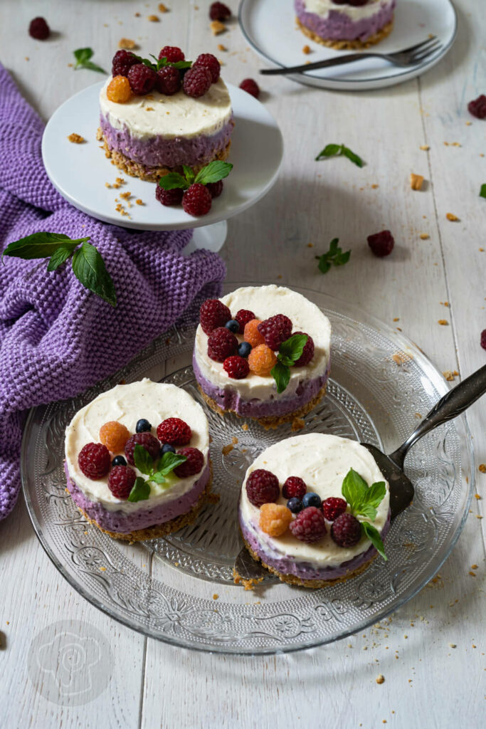 Mini-Cheesecakes mit Beeren auf einer Etagère und auf einem Glasteller