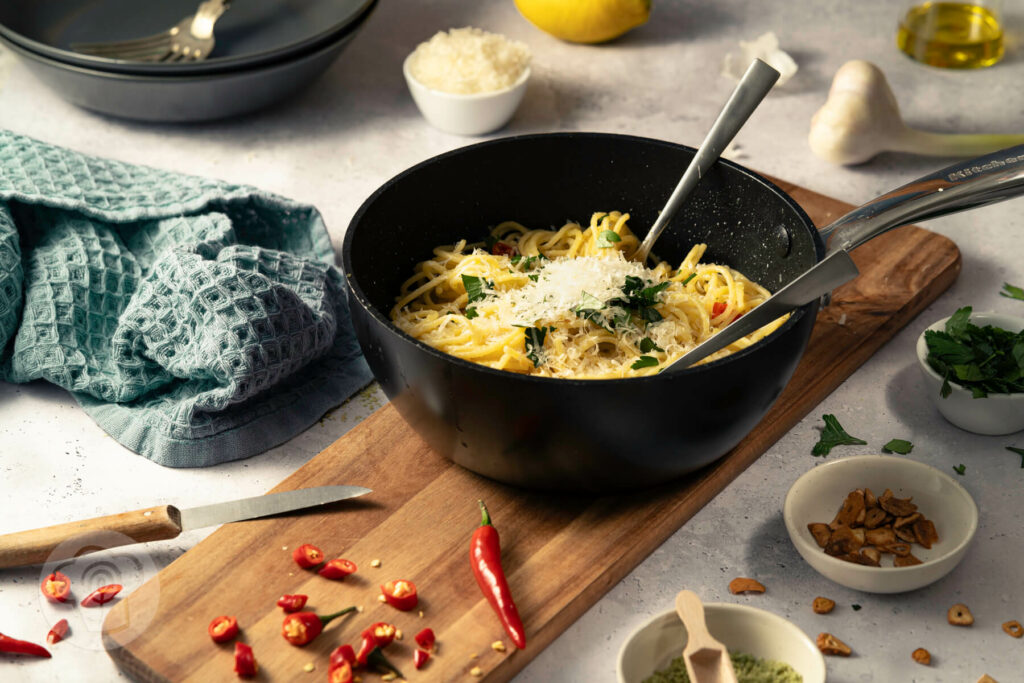Spaghetti aglio e olio - der italienische Klassiker, in der Pfanne mit Chili, gerösteten Knoblauchscheiben, Parmesan und Petersilie